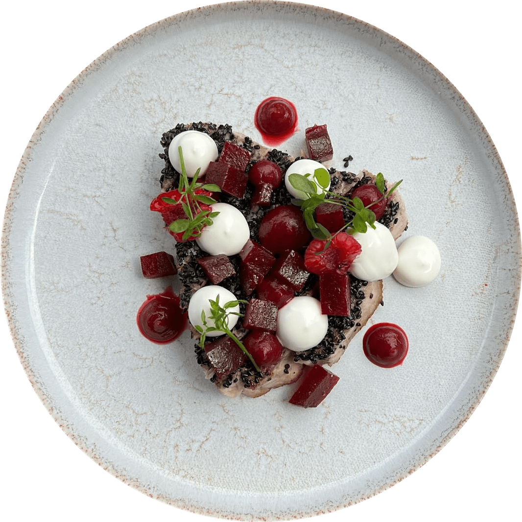 Betteraves vues du dessus sur une assiette blanche : dés et points de betterave, fromage frais, crumble noir, jeunes pousses.